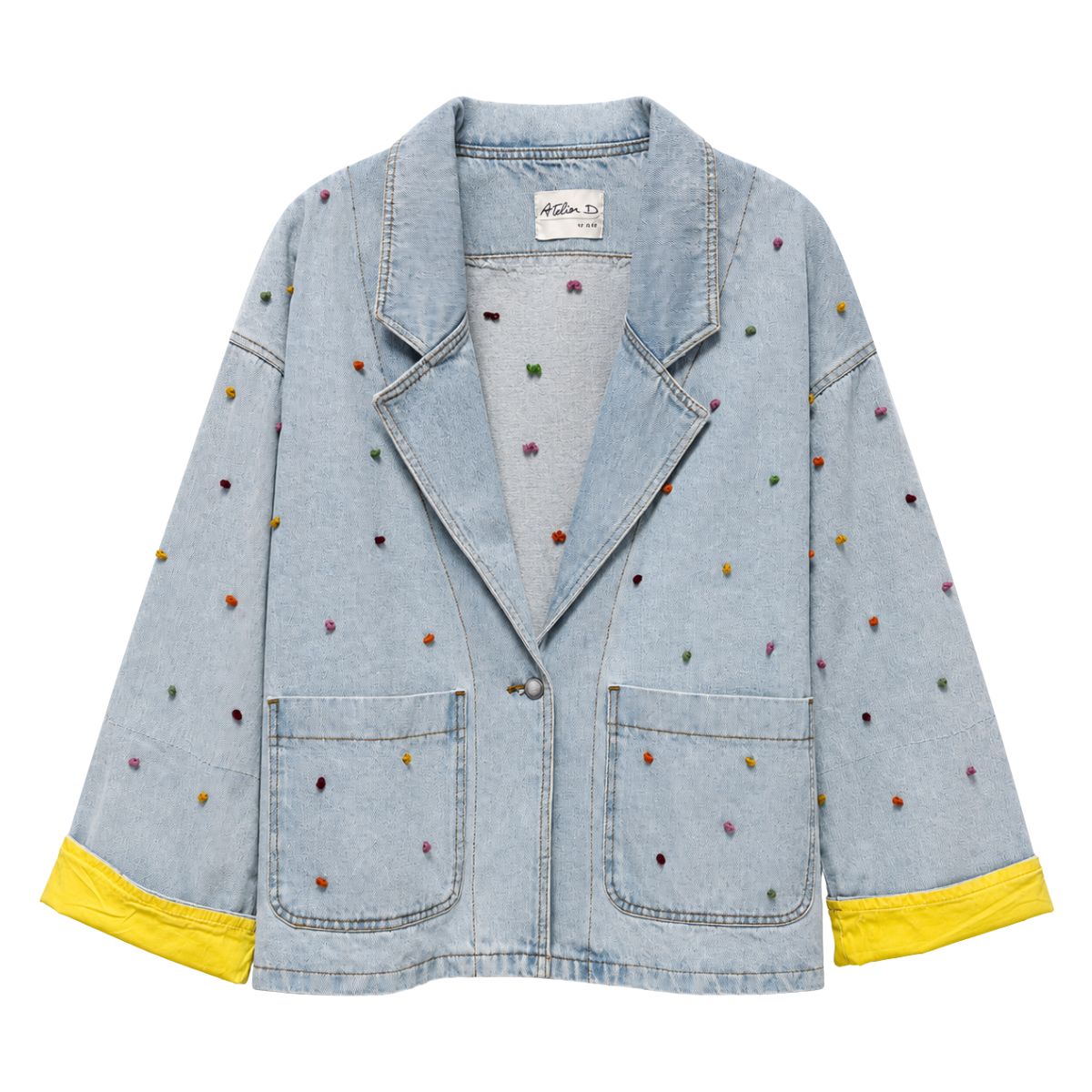 Flat front view of the Boutique Flo Confetti Embroidered Light Denim Jacket, showing multicolor embroidered dots across the light-wash denim with notched lapel collar, patch pockets, and folded yellow contrast cuffs