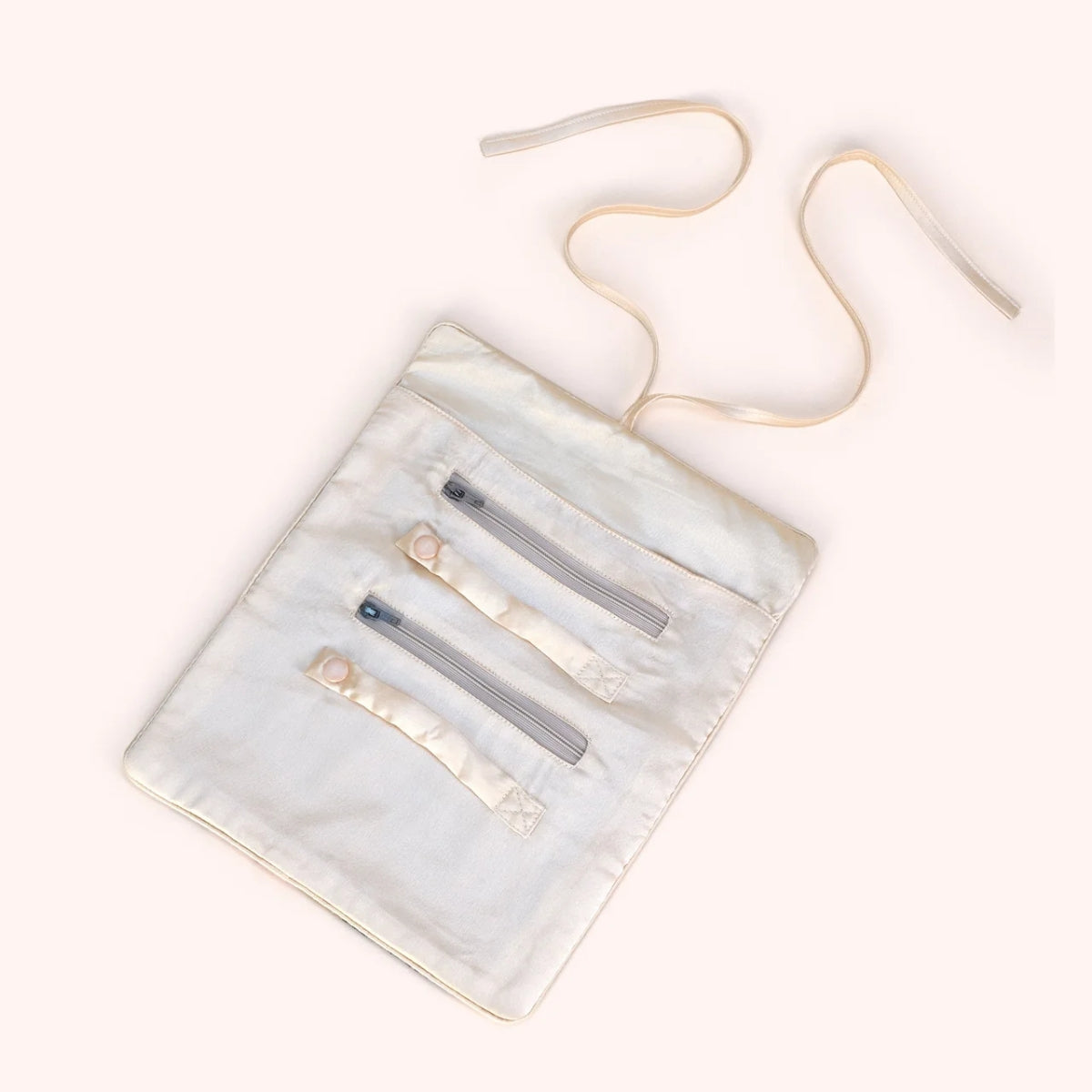 Interior view of the tulip jewelry roll unrolled, showing ring holders, zip compartments, and cream lining