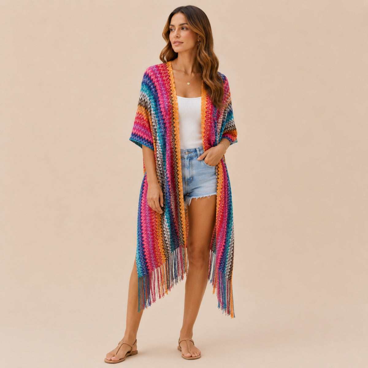 Front view of model wearing You & Eye vibrant pink chevron knit long kimono with fringe hem over denim shorts and white top