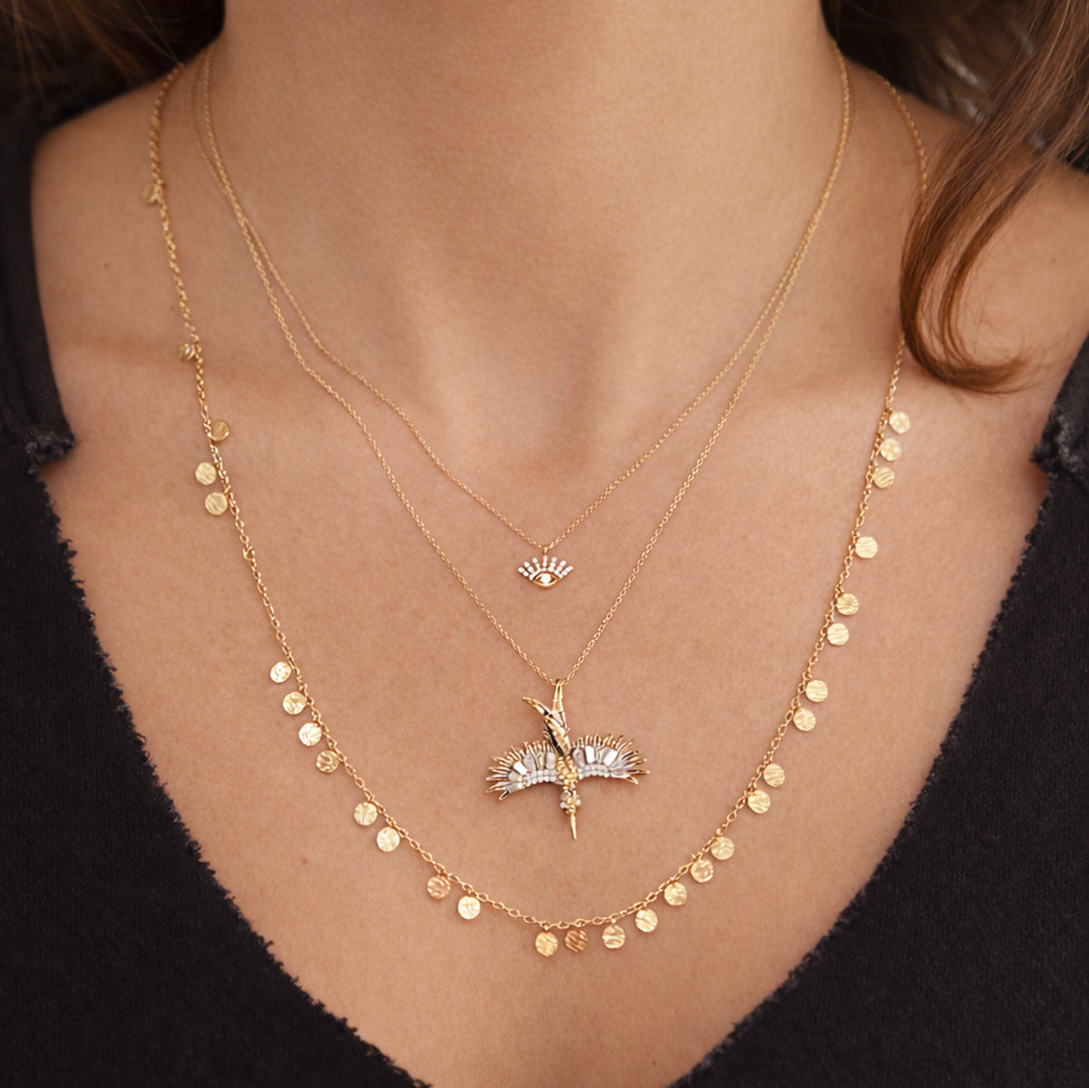 Close-up of layered gold necklaces with delicate chains and pendant charms worn together