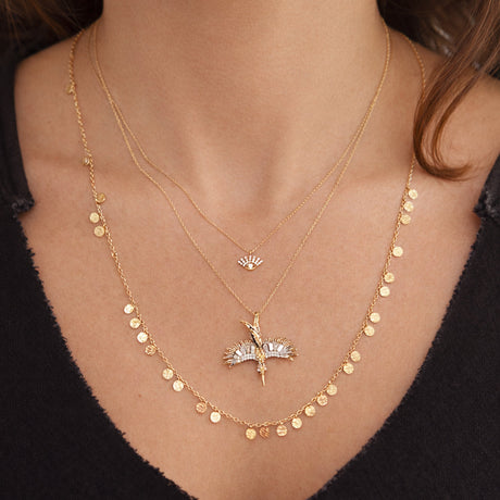 Close-up of layered gold necklaces with delicate chains and pendant charms worn together