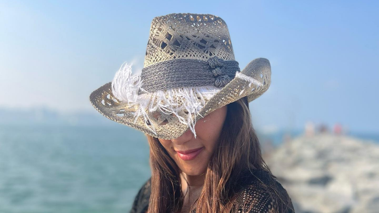 Woman wearing designer straw hat by the beach