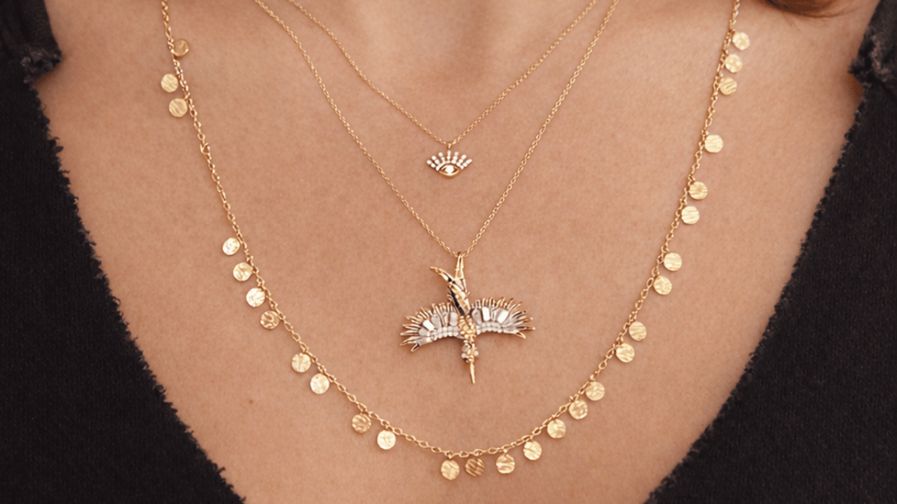 Close-up of layered gold necklaces with delicate chains and pendant charms worn together