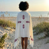 A woman wearing a white shawl with printed intricate patterns draped over her shoulders.