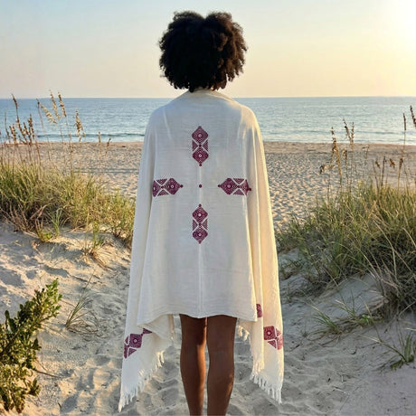 A woman wearing a white shawl with printed intricate patterns draped over her shoulders.