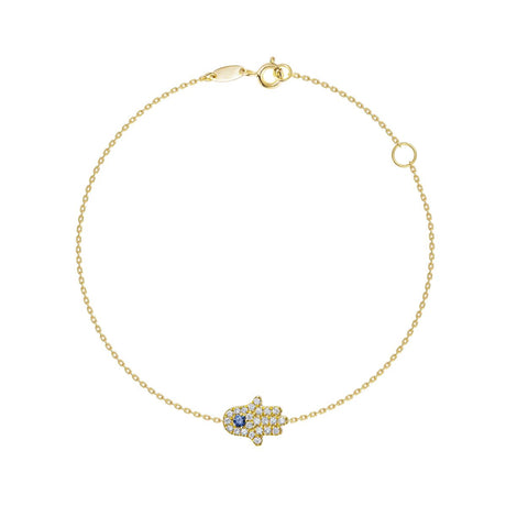 A delicate gold chain bracelet with a Hamsa hand charm paved with small clear stones and featuring a central blue gemstone, shown on a plain white background.