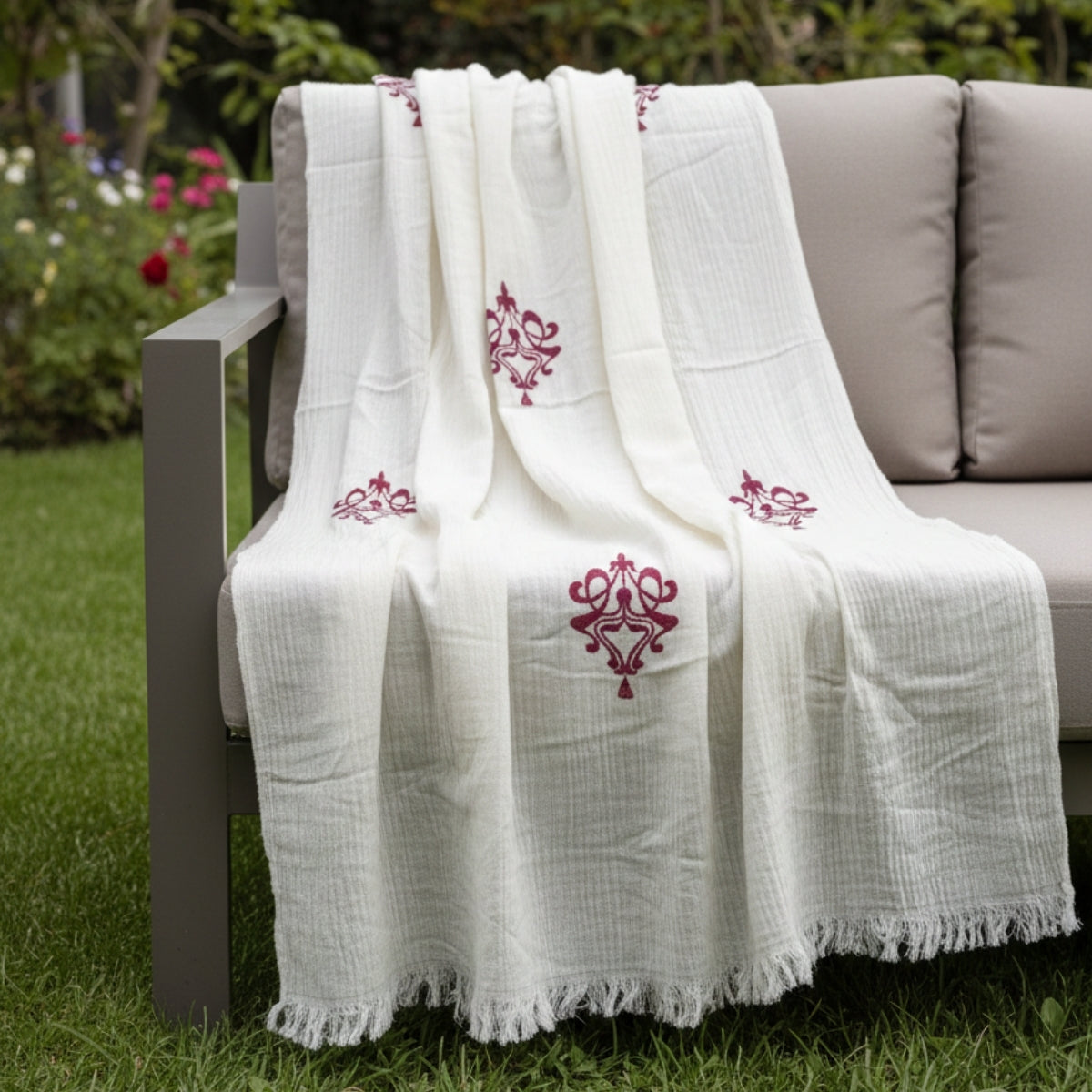 White printed shawl draped over a chair outdoors with greenery in the background