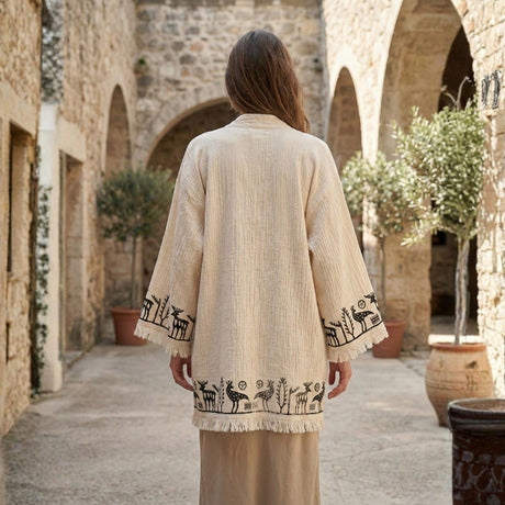Woman wearing a beige printed short kimono in a stone archway courtyard.