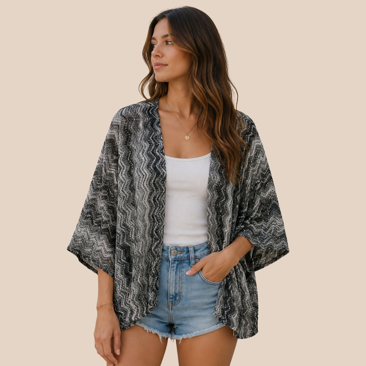 Woman wearing black and grey chevron knit poncho with open front and three quarter sleeves, styled as a resort wear beach cover up