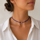 Woman wearing blue tiny beaded evil eye choker necklace with an evil eye bead, styled with a white collared shirt