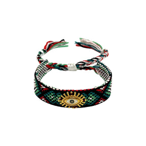 Woven friendship bracelet in black green and red geometric pattern with gold sunburst evil eye charm, adjustable pull cord closure