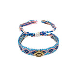 Woven friendship bracelet in blue pink and navy geometric pattern with gold evil eye charm and crystal detail, adjustable pull cord closure