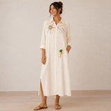 Front view of the Boutique Flo Good Vibes Embroidered White Shirt Dress worn by a model with rolled sleeves, side slit, and embroidered sun and palm tree detailing