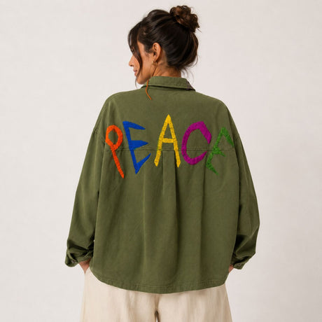 Back view of the Boutique Flo Peace Embroidered Green Jacket worn by a model, showing the hand-embroidered multicolor PEACE lettering across the olive cotton twill