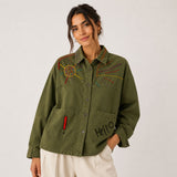 Front view of the Boutique Flo Peace Embroidered Green Jacket worn by a model, showing the relaxed oversized fit, collar, and embroidered sun and dash detailing