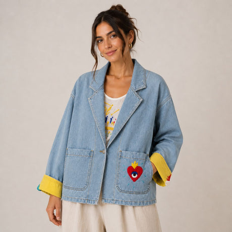 Front view of the Boutique Flo Super Mom Embroidered Light Denim Jacket worn by a model with cuffed yellow sleeves and embroidered sacred heart pocket detail