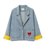 Flat front view of the Boutique Flo Super Mom Embroidered Light Denim Jacket, showing the notched lapel collar, patch pockets with embroidered sacred heart motif, and folded yellow contrast cuffs