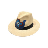 Side view of the City Girl Hand-Painted Hand of Fatima Wide Rim Hat, showcasing a hand-painted Hand of Fatima motif in navy, cobalt, and russet red with a central eye on the natural woven straw crown above a black grosgrain band
