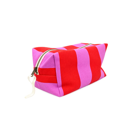Three-quarter angle view of the large Paola striped travel pouch showcasing its vibrant red and pink striped canvas.