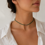 Woman wearing green tiny beaded evil eye choker necklace with a red and white evil eye bead, styled with a white collared shirt