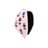 Pink headband hand embroidered with six single stem tulips in varying colors, black lining visible along the inner band