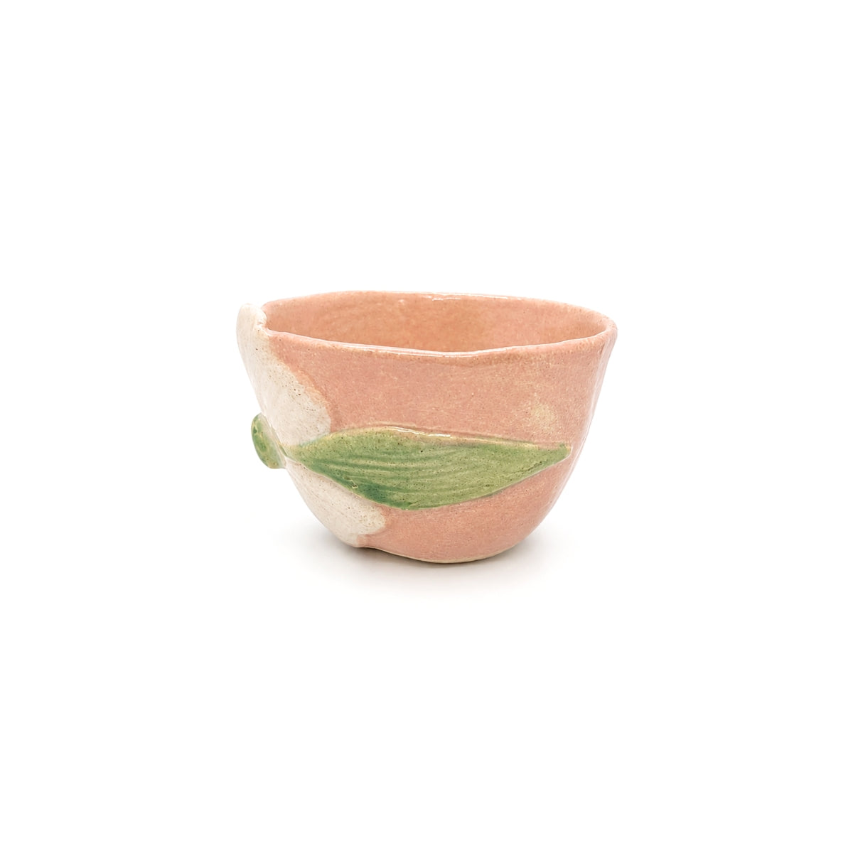 Side view of Nayla's Ceramics blush pink handmade bowl highlighting green leaf glaze accent and natural pottery texture