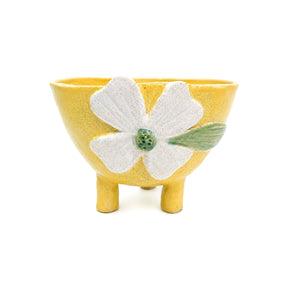 Front view of handcrafted footed yellow clover ceramic bowl with legs by Nayla's Ceramics featuring a raised off-white flower and green center