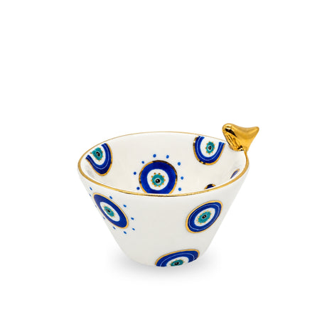 Side angle view of the white ceramic medium evil eye birdie bowl showing its internal and external painted motifs and gilded bird accent.