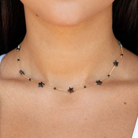 Model wearing Orchid Jewelry 18k yellow gold metallic stardom star station choker necklace along the neckline