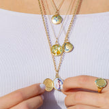 Model wearing Orchid Jewelry 18k yellow gold Moonlight locket necklace styled along the neckline