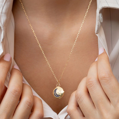 Model holding open the Orchid Jewelry 18k gold Moonlight locket necklace revealing a personal photo frame inside