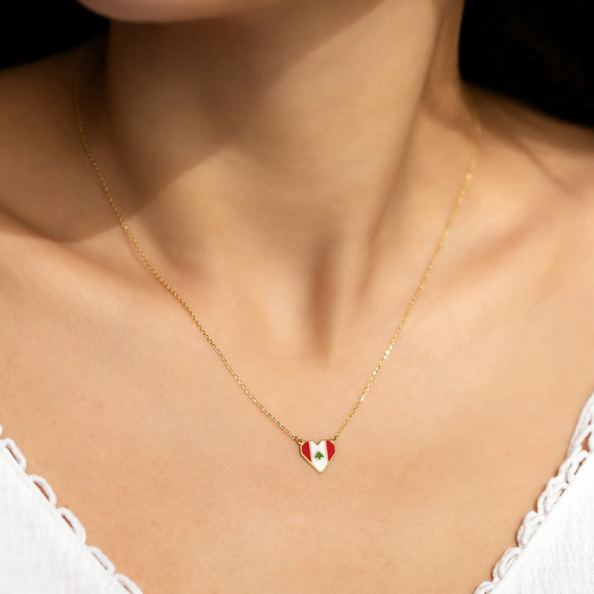 Model wearing Orchid Jewelry 18k yellow gold and enamel Lebanon flag heart necklace on a delicate gold chain