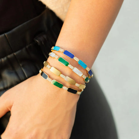 Model's arm displaying a stack of Orchid Jewelry 18k yellow gold geometric gemstone cuffs
