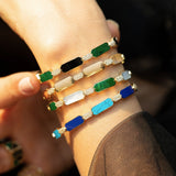 Close-up view of model wearing the Orchid Jewelry 18k gold malachite and mother of pearl diamond bangle stacked with colorful stone cuffs