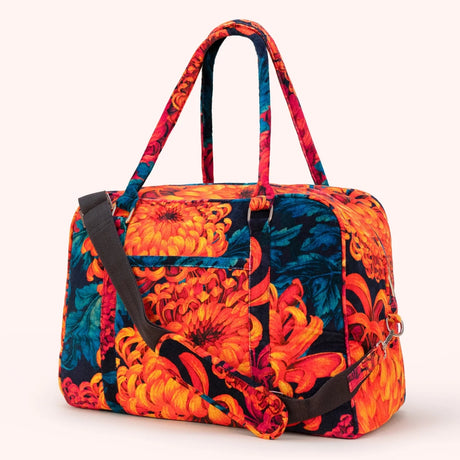 Orange and teal chrysanthemum print velvet weekend bag shown at an angle, with detachable strap and top handles visible