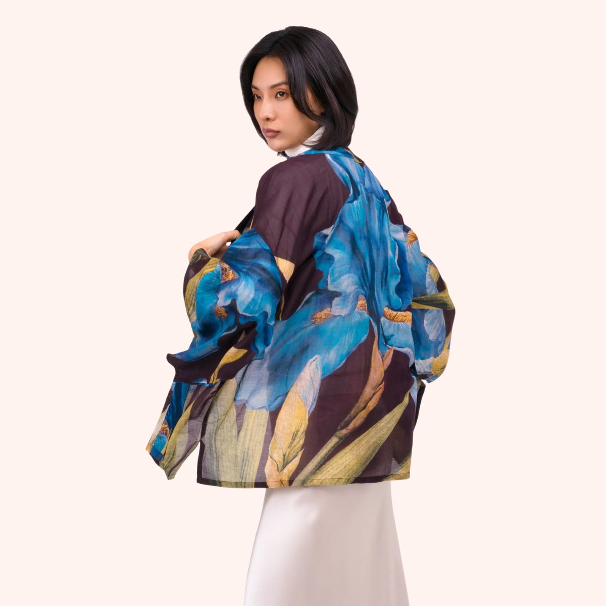 Model wearing a plum kimono jacket with blue and gold iris print, wide draped sleeves shown from behind