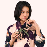 Model holding the plum orchid print jewelry roll against a matching printed robe