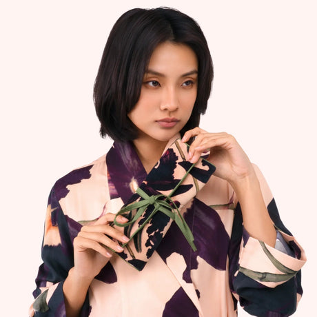 Model holding the plum orchid print jewelry roll against a matching printed robe