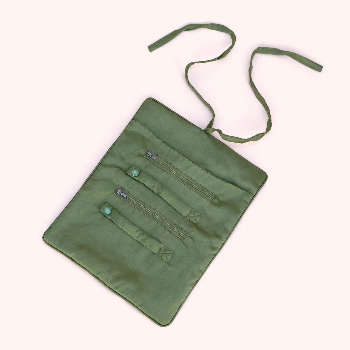 Interior view of the midnight orchid jewelry roll unrolled, showing ring holders, zip compartments, and moss green lining