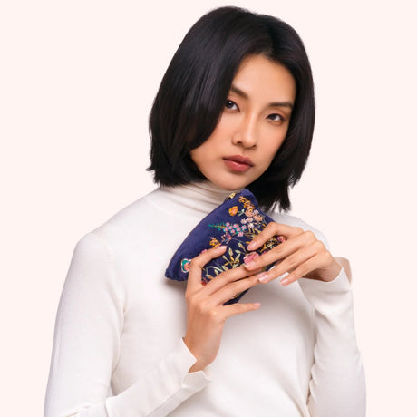 Model holding the navy velvet floral hedgerow mini pouch, showing the embroidered detail up close