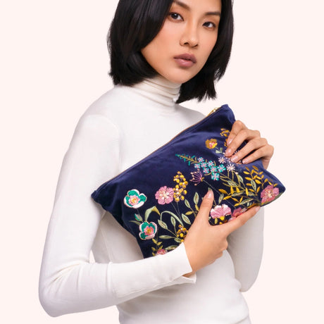 Model holding the navy velvet floral hedgerow zip pouch, showing the embroidered detail up close