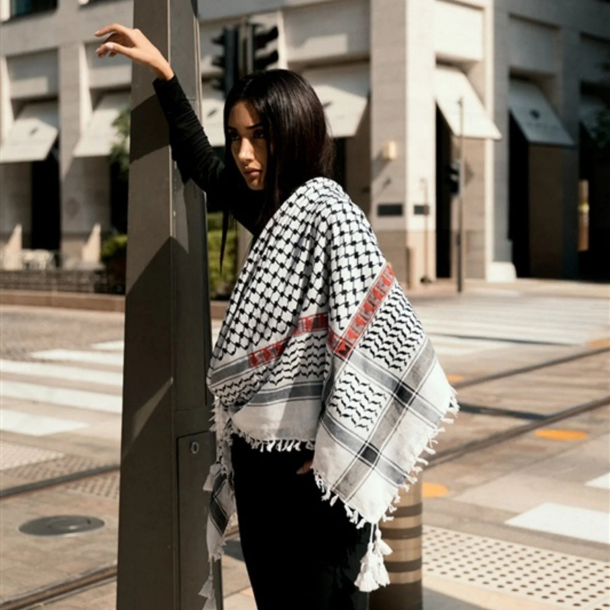 Front view of model wearing SEP black and white cotton keffiyeh scarf with red embroidery layered around the neck