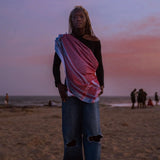 Model at the beach during sunset wearing SEP blue and red keffiyeh scarf styled draped across her torso