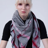 Front view portrait of model wearing SEP grey thalia keffiyeh scarf layered around her neck over a black top