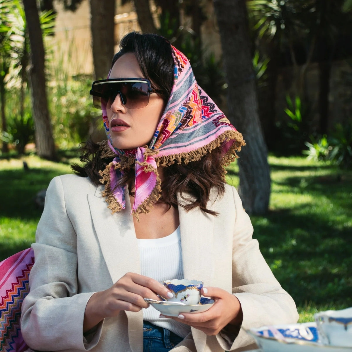 Model wearing SEP triangular mini pink multicolor keffiyeh scarf styled as an elegant headscarf tied around the neck