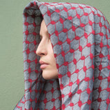 Close-up profile of model wearing SEP red and grey keffiyeh scarf draped over her head like a hood