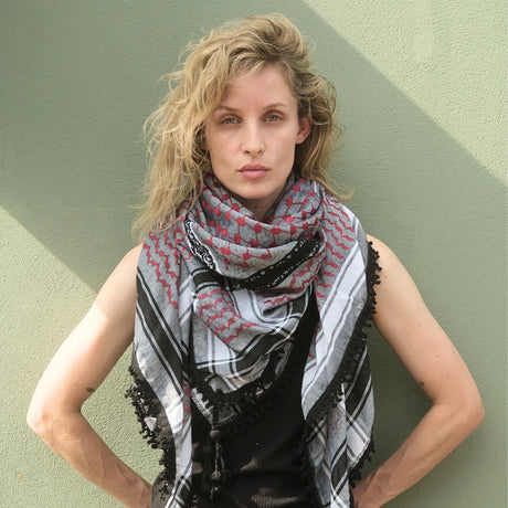 Model wearing SEP red and grey keffiyeh scarf layered around her neck posing against a sage green background