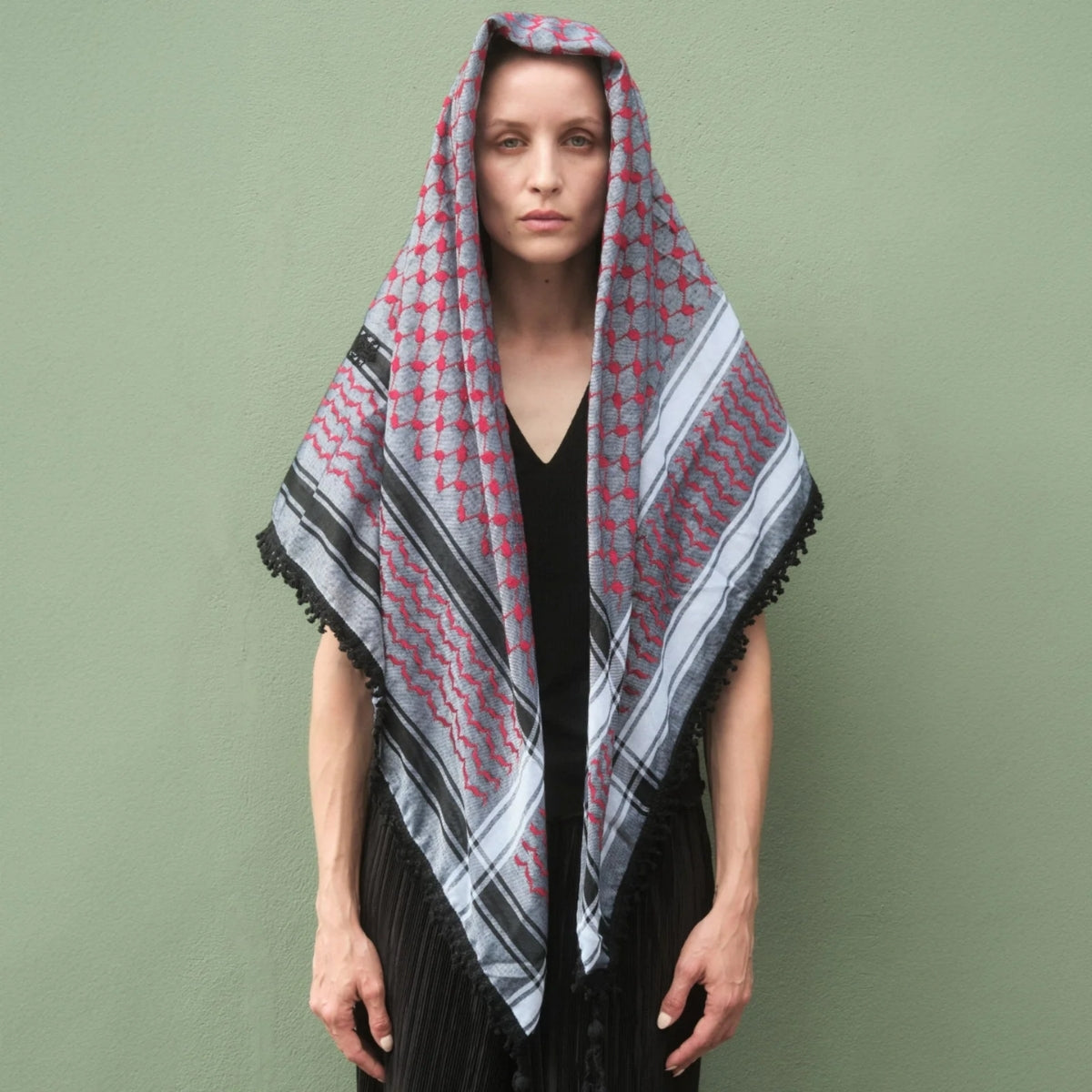 Front view portrait of model wearing SEP red and grey keffiyeh scarf draped over her head and shoulders as a shawl