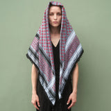 Front view portrait of model wearing SEP red and grey keffiyeh scarf draped over her head and shoulders as a shawl