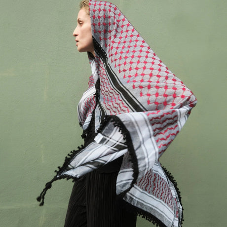 Model in motion wearing SEP red and grey keffiyeh scarf wrapped over her head with tassels catching the breeze